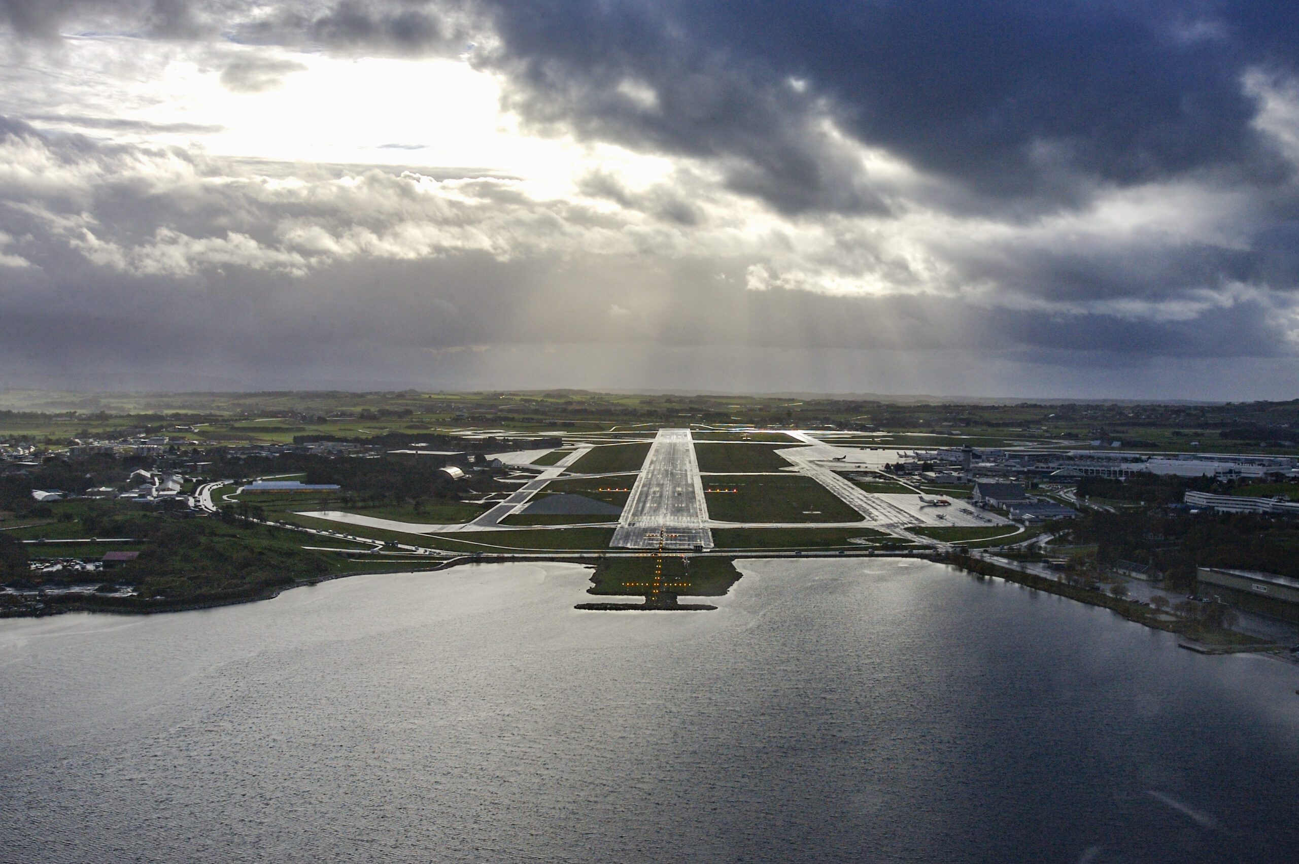 Flyfoto av Sola flyplass på Jæren, med rullebanen omkranset av flatt jærlandskap og sjø.