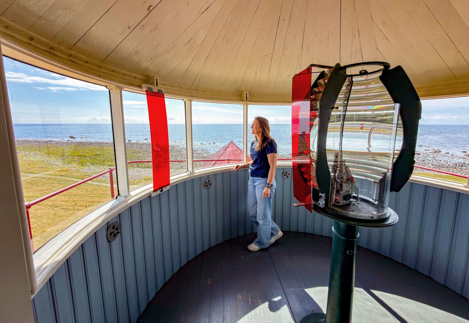 Oddrun Aksnes ved den gamle fyrlinsa i lyktehuset på Kvassheim fyr, med havet utenfor vinduene.